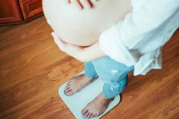 Image of woman weighing herself and experiencing weight gain through pregnancy Spring Bank
